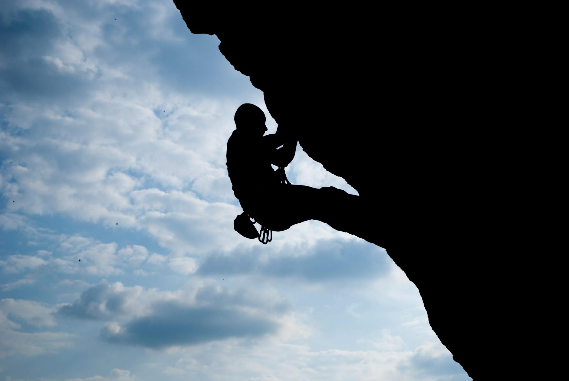 silhouette of man rock climbing